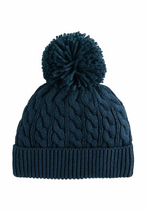 Navy blue knitted winter hat with cable pattern, folded brim, and large pom-pom on top.