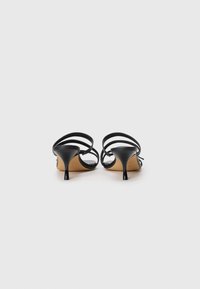 Black heeled sandals with multiple thin straps and pointed toes. Soft leather material and a 7 cm stiletto heel. Neutral-colored insole.