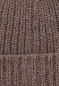 Brązowa dziana czapka z prążkowanym wzorem. Różni się pionowymi liniami i grubym mankietem na dole. Wykonana z miękkiego, textured materiału.