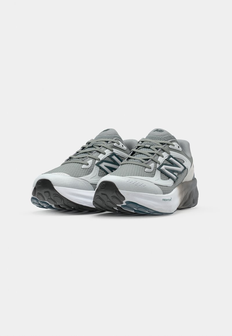 Lichtgrijze hardloopschoenen met een bovenwerk van mesh, getextureerde accenten en een chunky witte tussenzool. Voorzien van een zwarte rubberen loopzool voor grip.