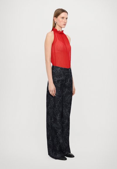 Rode kanten top met ruches aan de halslijn, gecombineerd met donkere, bloempatronen wijde broek. Gladde texturen en contrasterende kleuren.