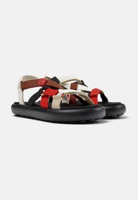 Strappy sandals with a black rubber sole, featuring multicolored nylon straps in red, brown, cream, and black for adjustable fit and support.