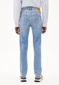 Lichtblauwe denim jeans met een rechte pasvorm, voorzien van achterzakken en een bruine leren merklabel op de taille.