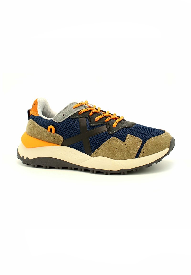 Zapatilla deportiva con parte superior de malla en color azul marino, acentos de ante gris, detalle en negro, cordones y lengüeta en color naranja, y suela robusta en gris.