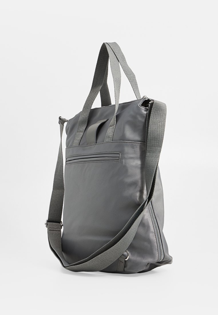 Graue Nylon-Tote-Tasche mit doppelten Stoffgriffen und einem verstellbaren Schultergurt. Verfügt über einen Reißverschluss oben und eine hintere Tasche für die Aufbewahrung.