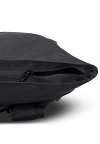 Sac en tissu noir avec une ouverture zippée, un design angulaire, une surface texturée et une poignée en boucle sur le côté pour un transport facile.