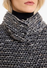 Flauschiger, grob gestrickter Rollkragenpullover in Grautönen, mit einem lockeren, strukturierten Design und bunten Farbklecksen sowie einem hohen, umgeschlagenen Kragen.