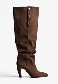 Botte en suède marron hauteur genou avec un bout pointu et un talon de 7,5 cm, présentant un design décontracté et deux boutons-pression argentés en haut.