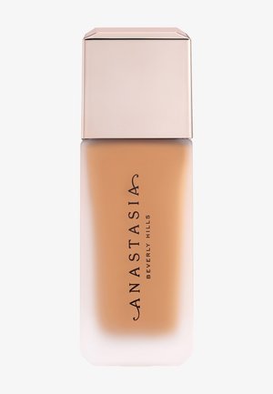 Base de maquillaje líquida mate beige en un frasco de vidrio esmerilado con una tapa cuadrada de color rosa pálido, etiquetada Anastasia Beverly Hills.
