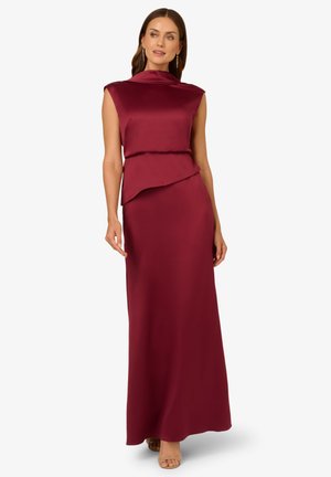 Abito da sera in satin bordeaux con colletto alto, maniche a cappuccio e design asimmetrico a strati. Texture liscia e silhouette lunga fino al pavimento.