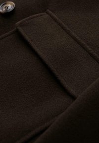 Donkerbruin wollen stof met een gladde textuur, voorzien van een zak en knoopdetails, met een gestructureerd ontwerp.