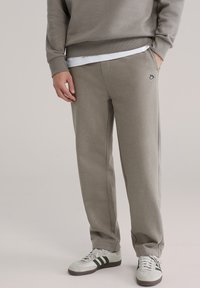 Grå joggingbukser med afslappet pasform, lavet af blødt materiale, med sidelommer og et lille logo på venstre hofte.