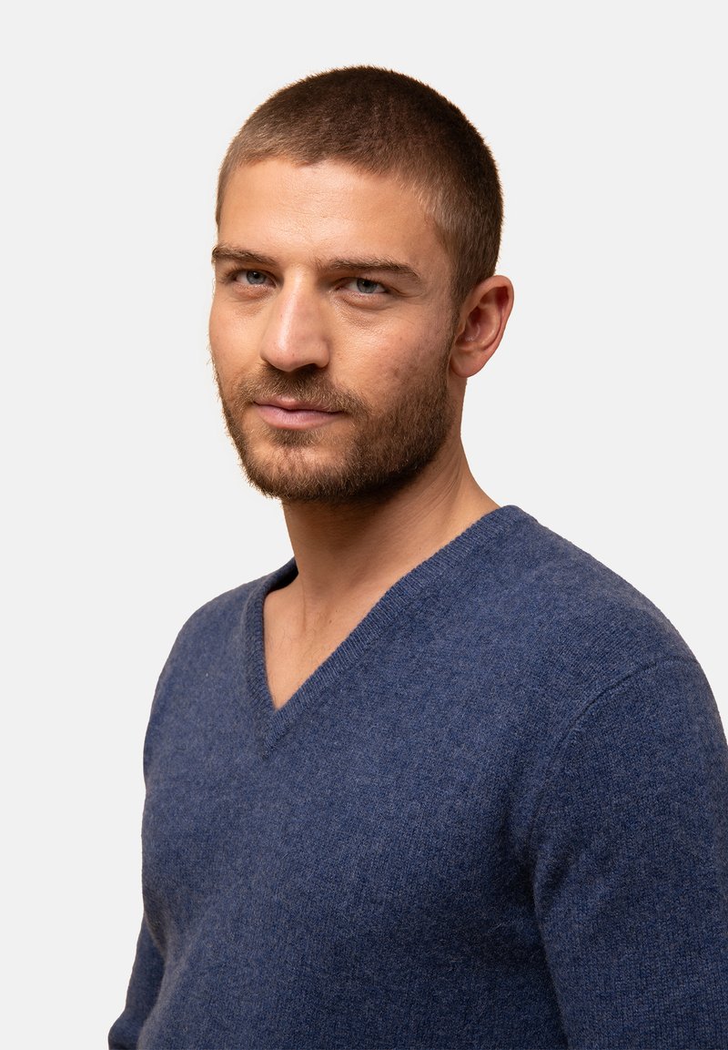 Navyblaues V-Ausschnitt-Pullover aus weichem Strickgewebe, mit langen Ärmeln und einem lässigen Schnitt. Minimalistisches Design ohne sichtbare Muster.