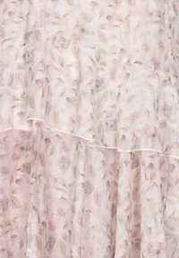 Tessuto rosa chiaro con un motivo floreale in tenui tonalità pastello. Il materiale ha una texture leggera e fluida con orli arricciati.