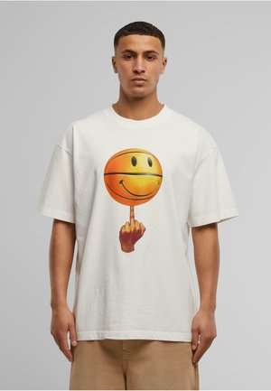 Fehér pamut póló, amelyen egy narancssárga mosolygós kosárlabdát tartó kéz grafika látható, az egyik ujj felfelé mutat.