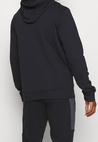 Hoodie bleu marine foncé à coupe décontractée, avec une grande capuche, des poignets et un ourlet côtelés, et une texture douce en mélange de coton. Vue arrière.