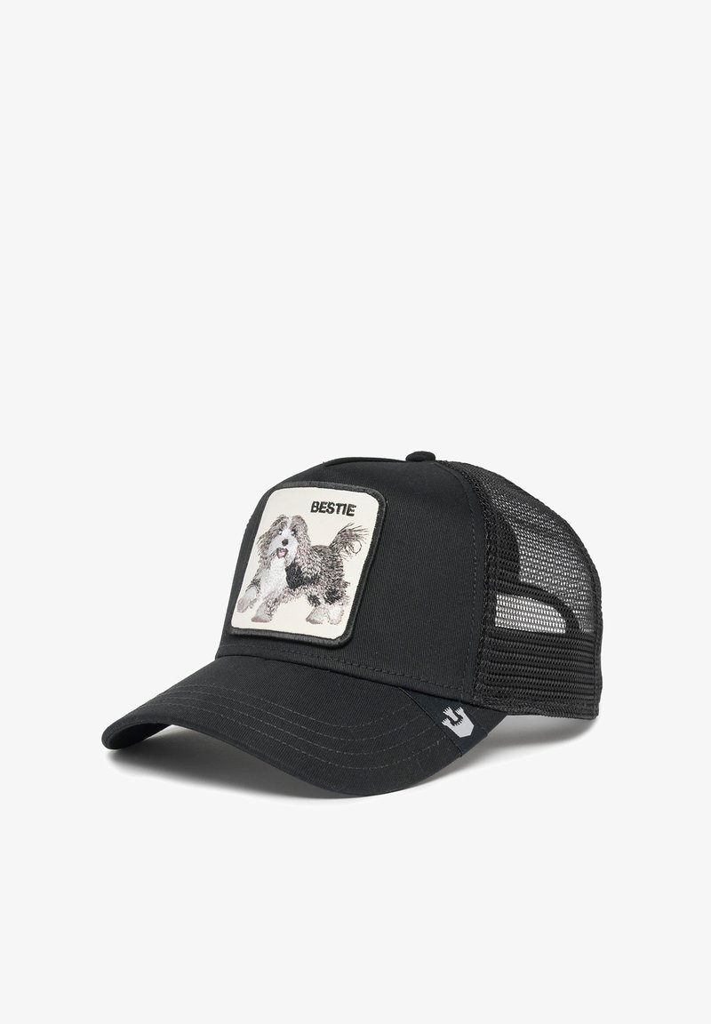 Gorra negra con malla en la parte posterior, que presenta un parche cuadrado con un diseño bordado de un perro y la palabra "BESTIE" arriba de la imagen.