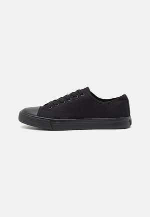 Black canvas sneakers with a round rubber toe cap and flat laces. Features a textured upper and a durable rubber sole.