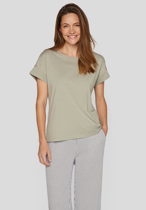Hellgrünes T-Shirt mit kurzen Ärmeln und lockerer Passform, verziert mit kleinen Strasssteinen in einem Muster. Kombiniert mit gestreiften, weiten Hosen.