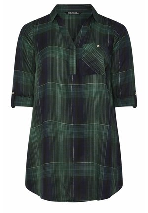 Camicia a quadri verde e blu navy con colletto, maniche arrotolabili e una tasca sul petto. Realizzata in tessuto leggero e testurizzato.