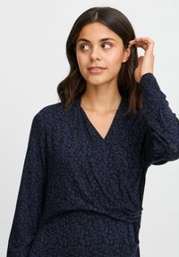 Tengerészkék, hosszú ujjú bodycon ruha, finom levélmintával sötétkéken. Puha anyagból készült, enyhe fényességgel.