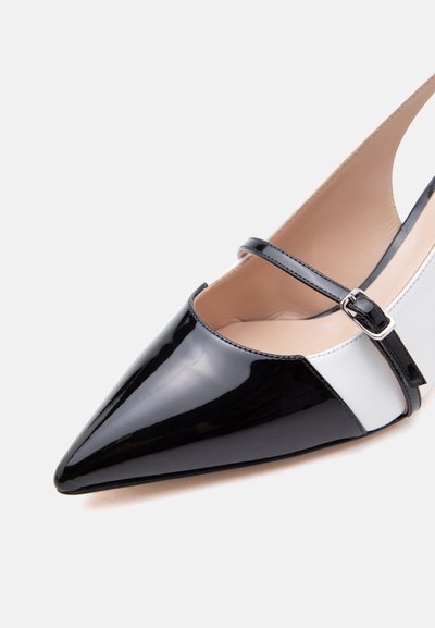 Μαύρο και λευκό μυτερό φλατ παπούτσι από δερμάτινο βερνίκι με λεπτό μαύρο λουράκι και ασημένια αγκράφα.