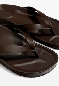 Barna gumipapucs keskeny, lapos pántokkal és formázott talpbetéttel. A talp texturált a jobb tapadás érdekében, az egész kialakítás egyszerű.