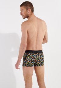 Men's boxers in black with a multicolored floral pattern, featuring a black waistband. The fabric appears soft with a smooth texture.
