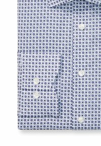 Ein Hemd mit Knopfleiste, das eine weiße Basis mit einem blauen und lila geometrischen Muster aufweist. Mit einem umschlagbaren Kragen und zwei weißen Knöpfen.