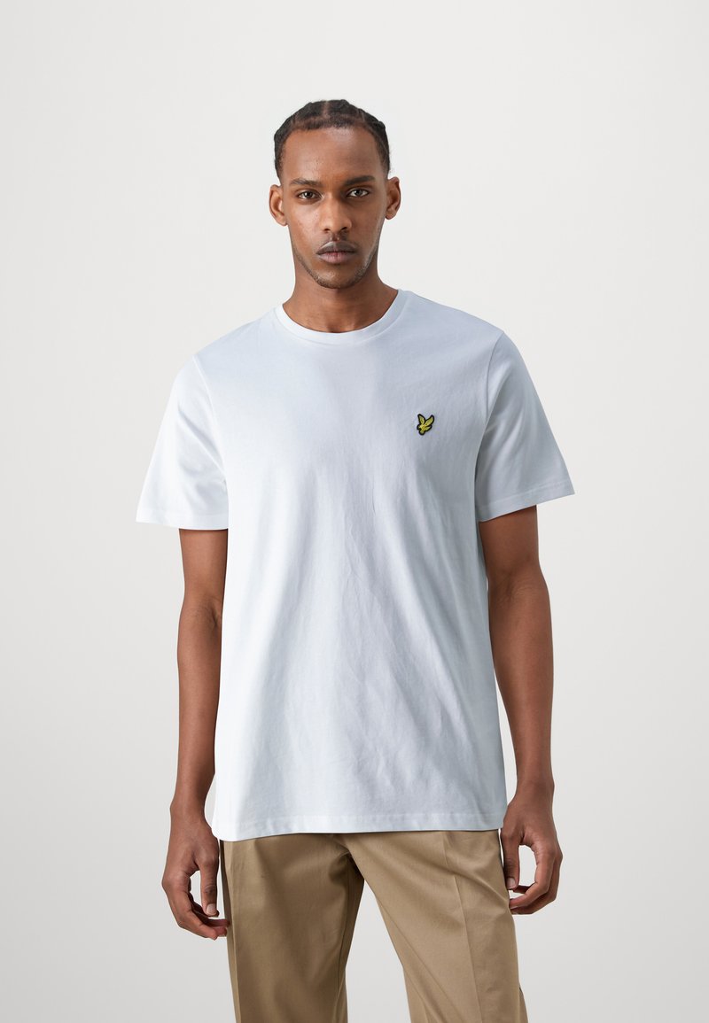 T-shirt di cotone azzurro chiaro con scollatura rotonda e maniche corte, caratterizzata da un piccolo logo di una farfalla gialla ricamato sul petto.