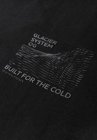 Černé bavlněné tričko s šedou vlnitou grafikou hory a textem "GLACIER SYSTEM OG" a "BUILT FOR THE COLD."