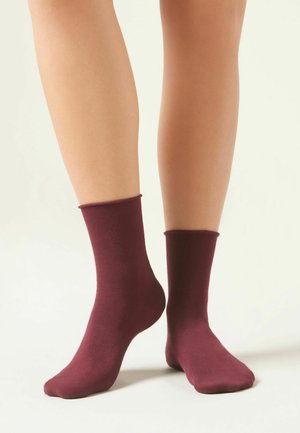 Calzini in cotone bordeaux a girocollo, texture liscia, sagomati alla caviglia, con un design semplice e senza motivi visibili o accessori.