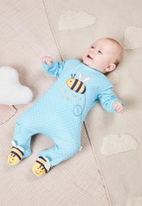 Hellblaues Pünktchen-Overall mit einem Bienenmotiv in Gelb und Schwarz. Enthält lächelnde Bienenakzente an den Füßen. Aus weichem Stoff.