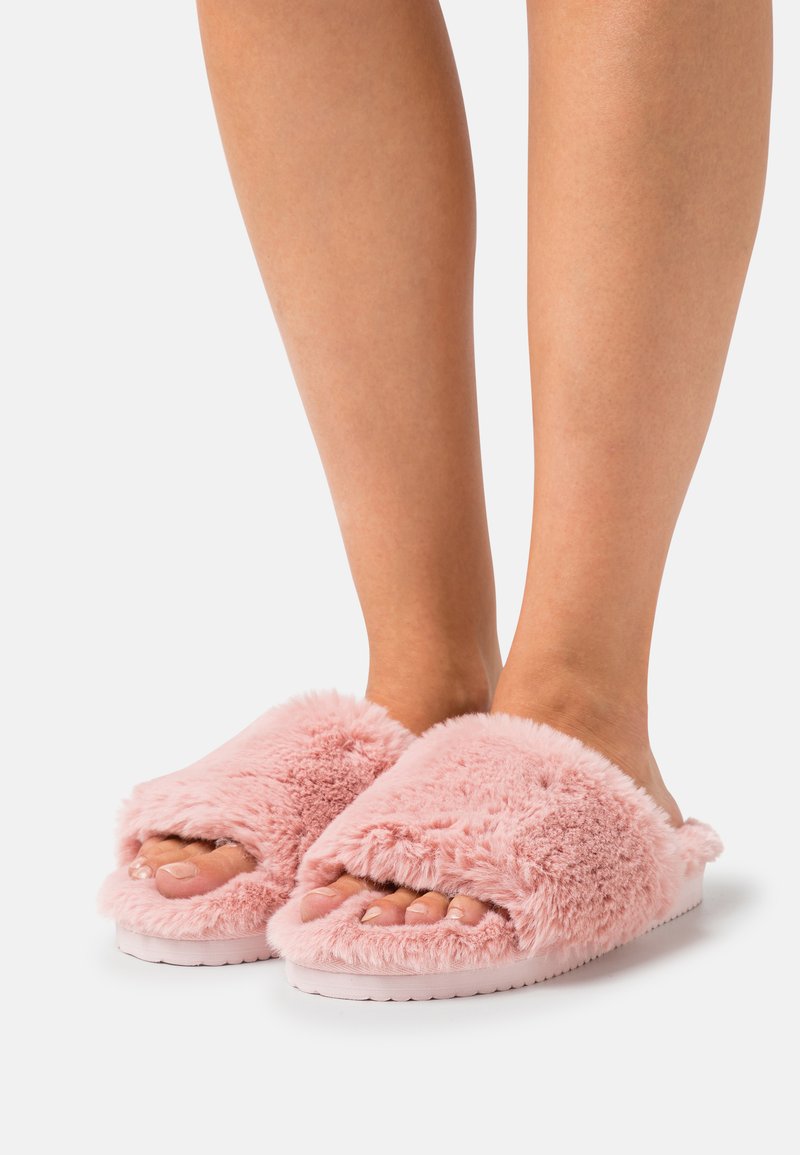 Pink fluffy slippers with an open toe design feature soft, textured fabric and a cushioned sole for comfort.