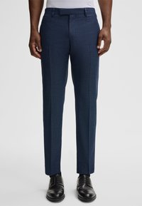 Marineblau maßgeschneiderte Hosen aus einem strukturierten Gewebe, mit flachem Bund, Seitentaschen und schmalem Schnitt, kombiniert mit schwarzen eleganten Schuhen.