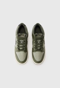 Grønne sneakers med en tekstureret overdel, glat tåboks, perforeringer og mørke accenter. Har flade snørebånd og en hvid gummisål.