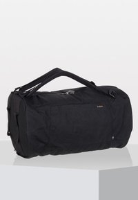 Black duffel bag made of durable fabric, cylindrical shape, zip closure, two top handles, and side pocket with a subtle logo detail.