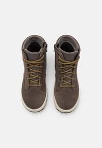 Botines de ante marrón con cordones amarillos, cremalleras laterales y suelas de goma. Presentan un cuello acolchado para mayor comodidad y soporte.