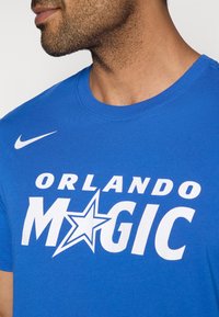 Blaues Baumwoll-T-Shirt mit großem weißen Schriftzug "ORLANDO MAGIC" und einem Stern-Design sowie einem kleinen weißen Nike-Logo auf der Schulter.