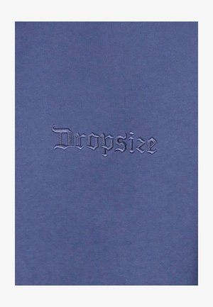 Tejido de algodón azul oscuro con la palabra "Dropsize" en un bordado estilizado y ligeramente en relieve. Textura suave con un brillo sutil.