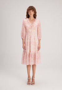 Robe à imprimé floral en rose clair avec un décolleté en V et un col volanté. Caractéristiques : manches trois-quarts et ourlet à volants.