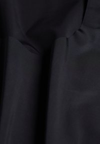 Zwarte stof met een gladde, matte textuur, met subtiele plooien en een zachte glans, geschikt voor kleding of bekledingsdoeleinden.
