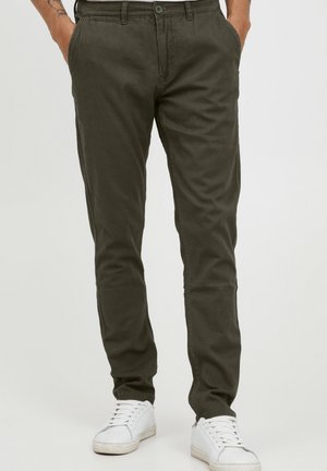 Olive green chinos made of soft cotton material, featuring straight legs, a button closure, and front pockets, paired with white sneakers.