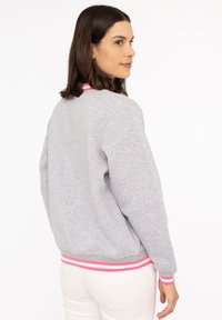 Grauer Sweatshirt mit gerippten rosa und weißen Akzenten am Kragen und Saum. Verfügt über lange Ärmel und eine lockere Passform. Rückansicht dargestellt.