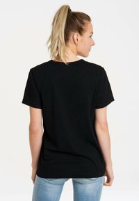 Black cotton t-shirt with short sleeves, round neckline, and a simple design. Viewed from the back, with light blue jeans.