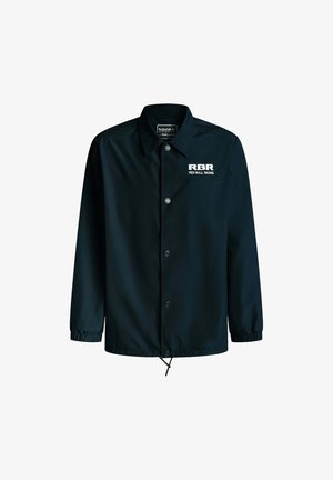 Chaqueta negra hecha de tela suave, con un cierre frontal de botones, puños elásticos y el logo "RBR" en blanco en la parte izquierda del pecho.