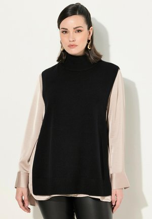 Maglione a collo alto nero in maglia, indossato sopra una blusa in satin beige chiaro, con maniche lunghe e orlo a coste, abbinato a pantaloni in pelle nera.