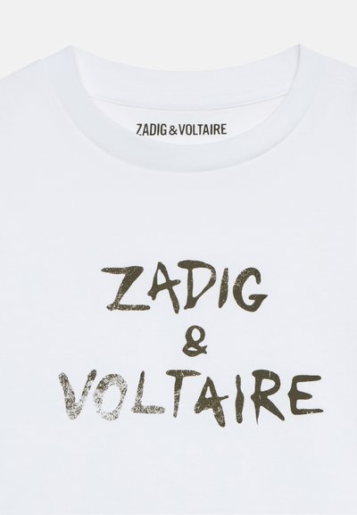 Tricou alb cu guler rotund, cu text negru în stil scris de mână „ZADIG & VOLTAIRE” pe partea din față și pe eticheta interioară a gulerului.