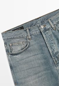 Jasnoniebieskie dżinsy denimowe z klasycznym projektem pięciu kieszeni, wyposażone w zapięcie na guzik oraz efekt sprania. Metka widoczna wewnątrz pasa.