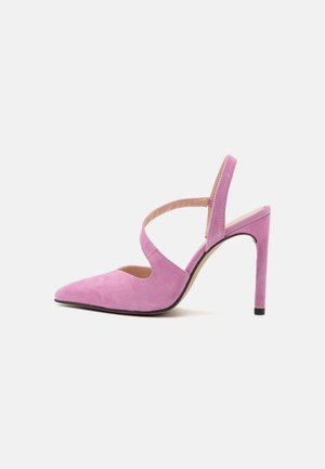 Chaussure à talon haut en daim rose avec bout pointu, bride arrière et détail croisé sur fond blanc.